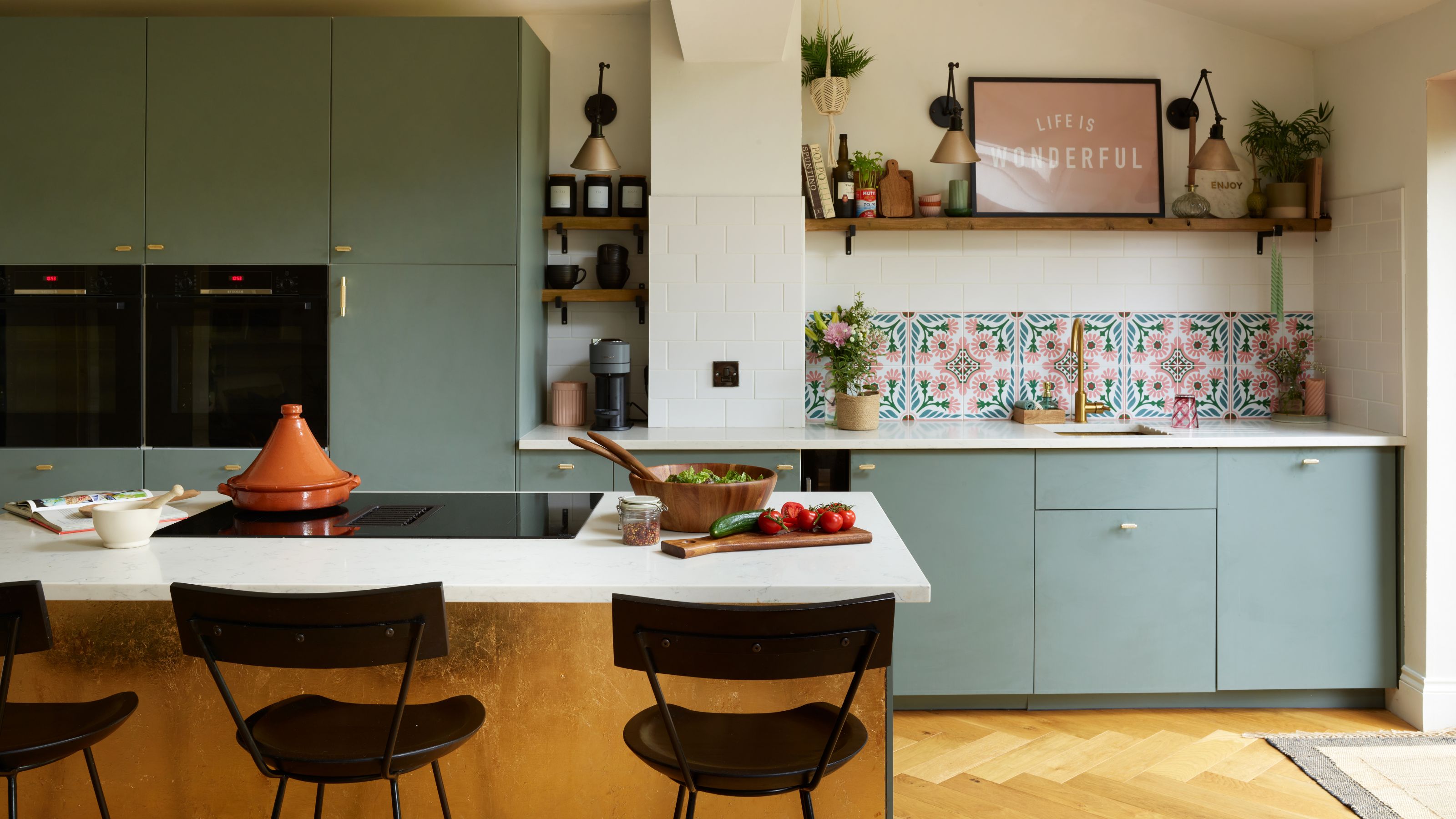 white painted kitchen with blue cupboards, wooden floors and a white kitchen island with a gold base
