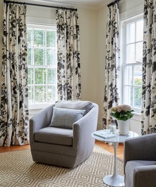 neutral living room with gray swivel chairs, white tulip table and floral drapery fabric