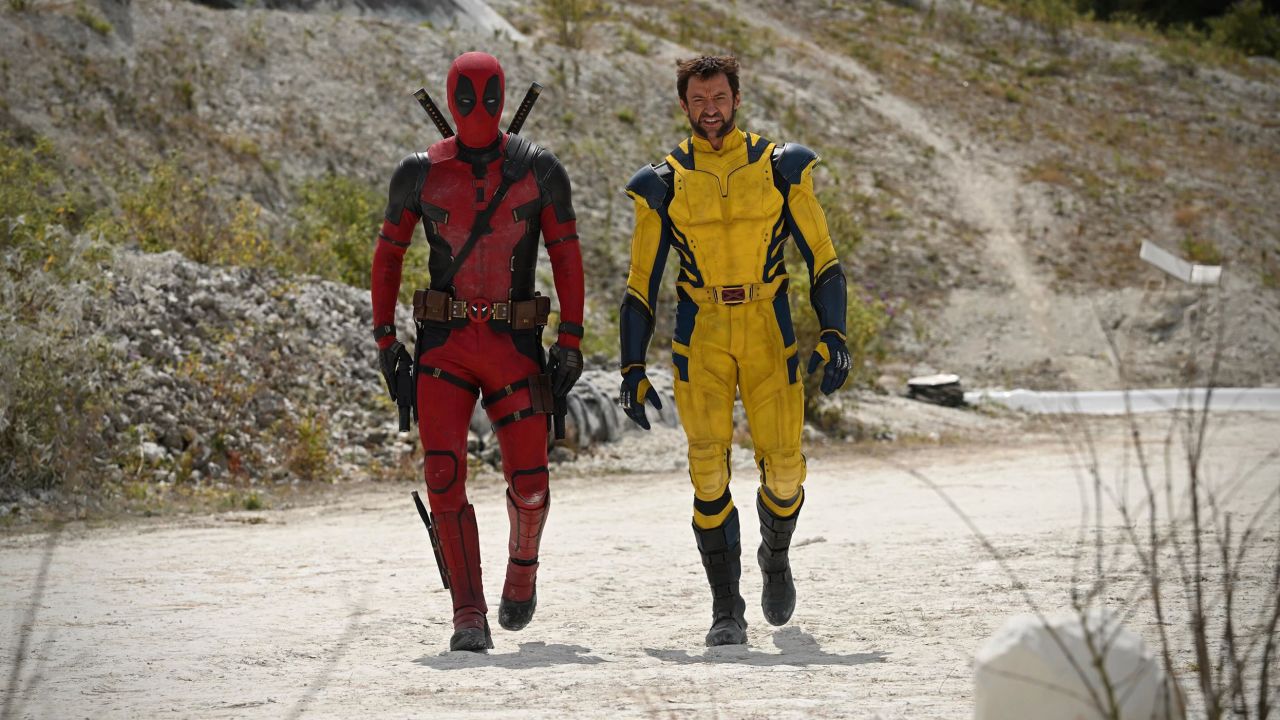 Deadpool and Wolverine walk down a dirt road in their classic comic book costumes in Deadpool 3