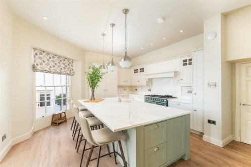 A kitchen with a lime green island and wooden panelled floor