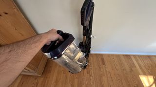 Shark POWERDETECT Upright Vacuum on wooden floor, revealing the dust bin