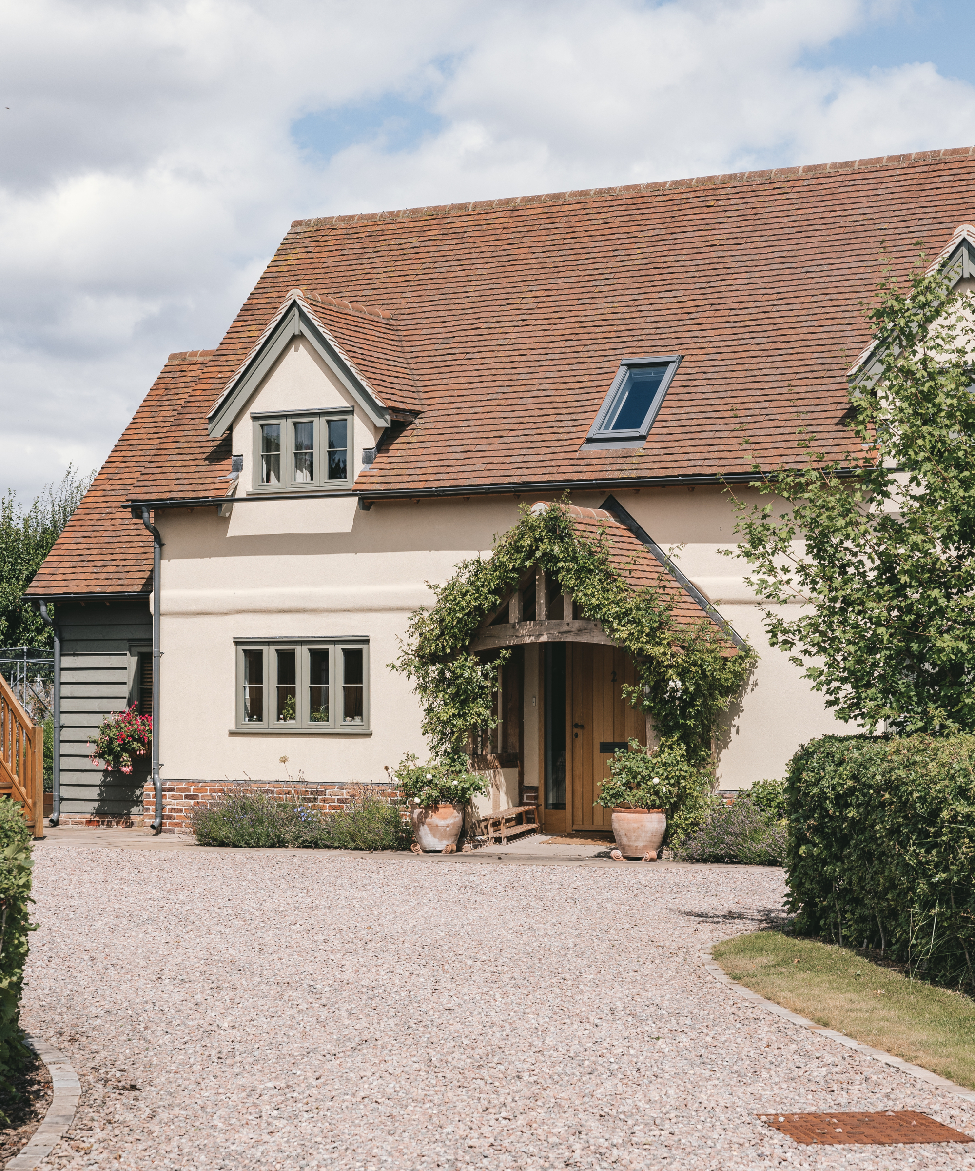 oak frame porch on cream rendered cottage with tiled roof, planting around front of oak frame