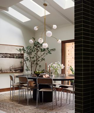 A dining room with skylights, a gold lamp and a large tree in the corner