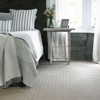 bedroom flooring ideas, natural flooring with herringbone design, wooden cladding, white and grey bedding, weathered wood stool, white curtains