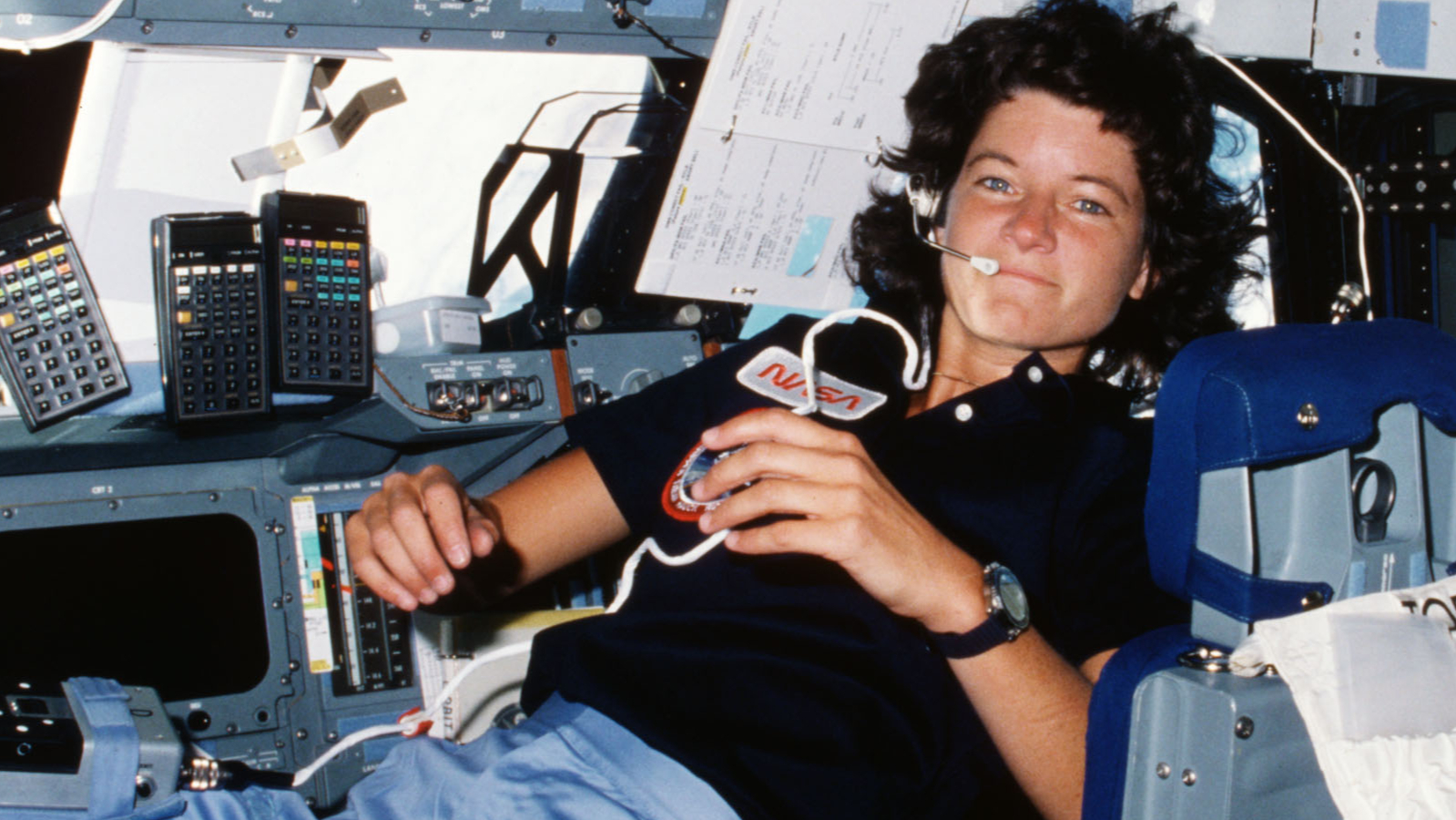 A woman with dark hair and a dark shirt floats in space.