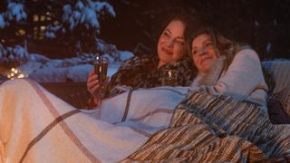 Kate and Tully sit under a blanket by a fire in Firefly Lane