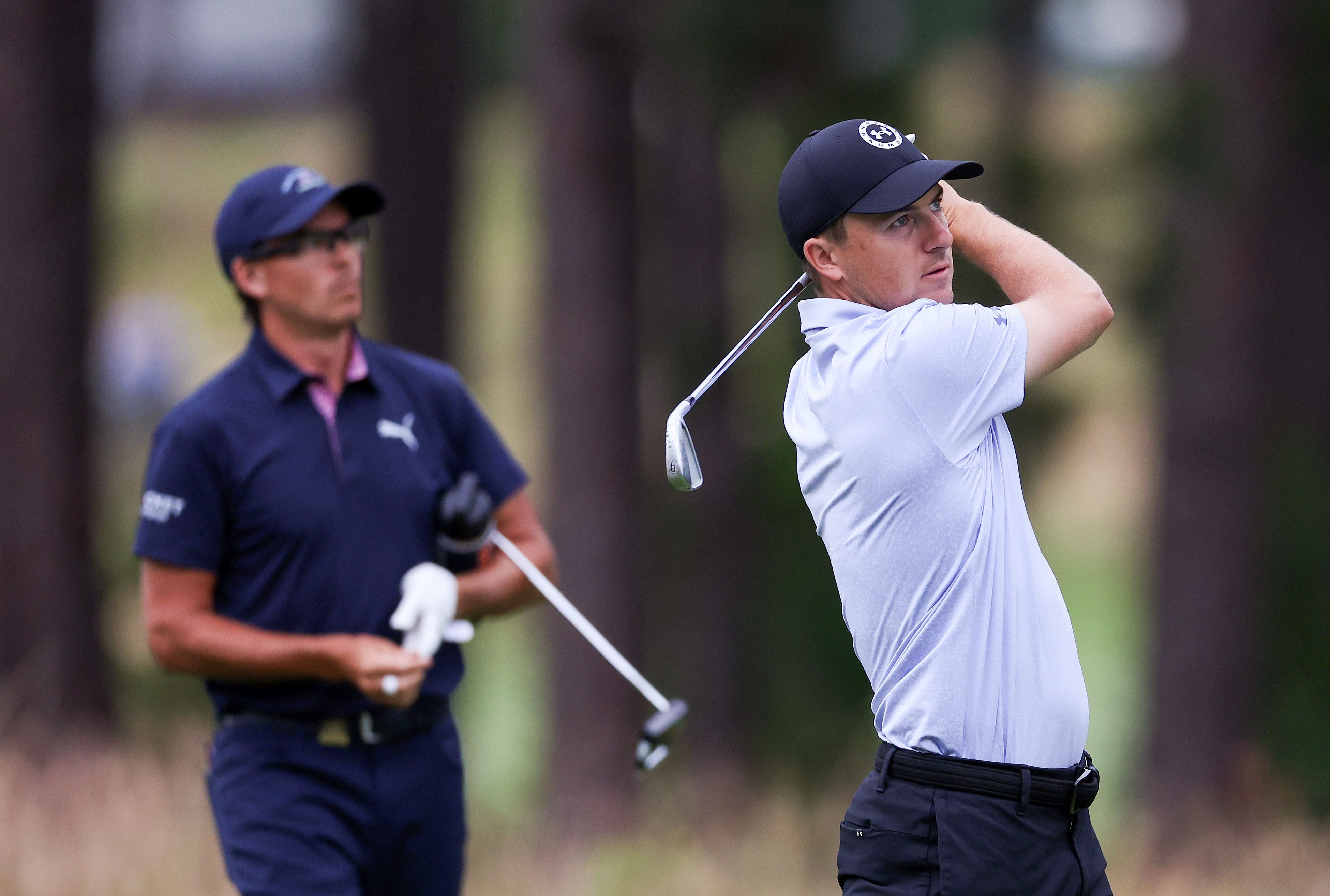 Jordan Spieth hits a shot, Rickie Fowler watches on