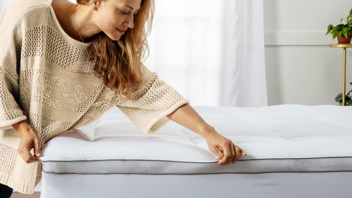 A woman placing the Viscosoft Hybrid Lux mattress topper on her mattress