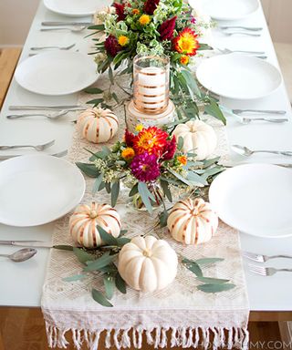 A thanksgiving-style table with white pumpkins and glasses decorated with copper foil
