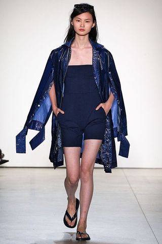 Model wearing a coat open walking down the runway