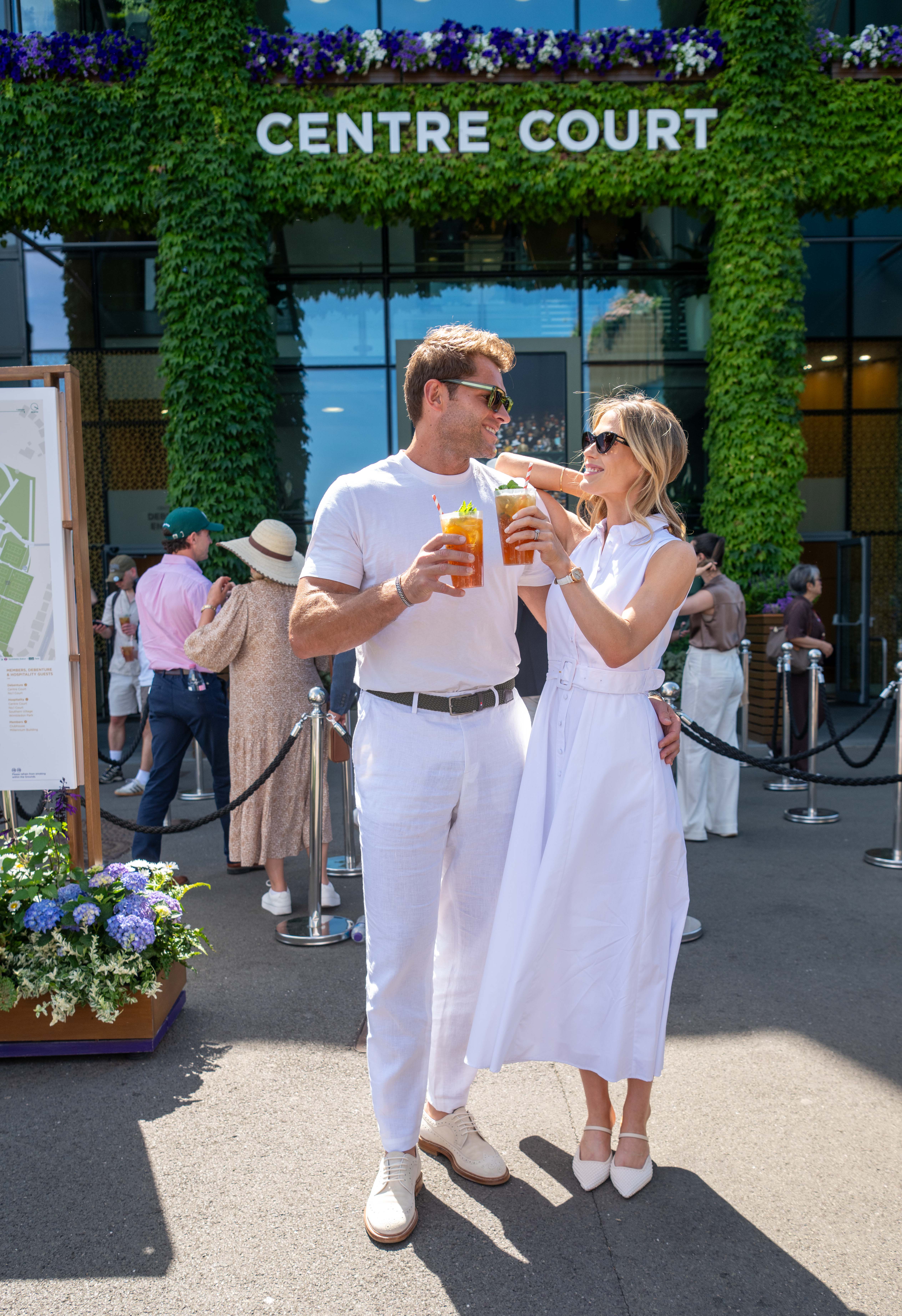 Amelia Spencer and Greg Mallett toasting in front of Centre Court at Wimbledon