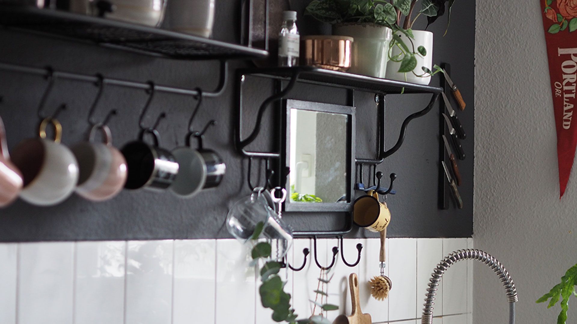 Monochrome kitchen with shelving and utensil rail with hanging mugs to show how to organize a small kitchen well