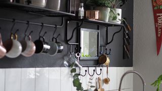 Monochrome kitchen with shelving and utensil rail with hanging mugs to show how to organize a small kitchen well