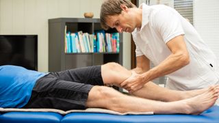 A man giving a sports massage to an athlete&#039;s calf muscles