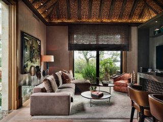 A living room with brown walls and a vaulted ceiling with wooden beams and gold accents