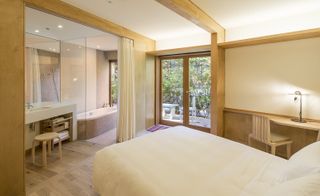 Bedroom and en-suite bathroom in natural, wood tones with exposed wood beams