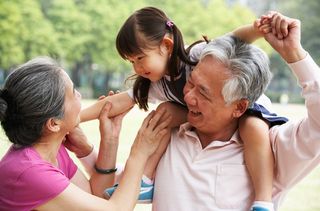 Grandparents carry their granddaughter.