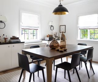 Modern dining room space with dark, rectangular dining table, and pendant lighting