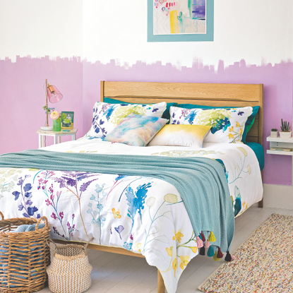 White floral bedding set on a double bed in a pink and white painted bedroom.