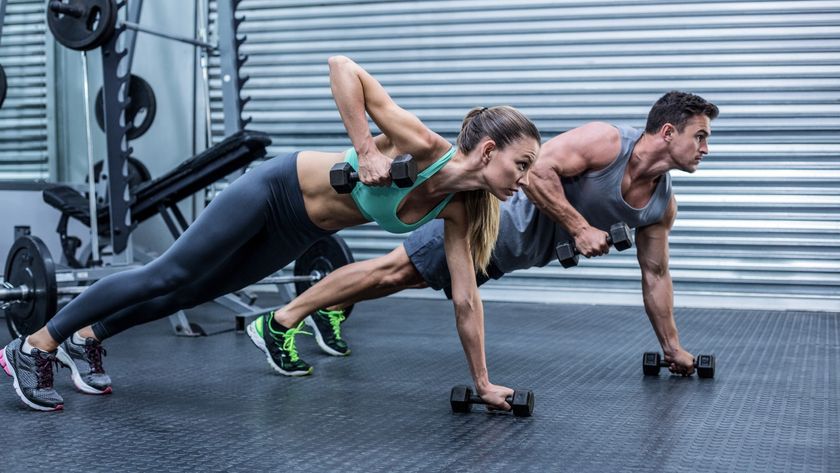 Man and woman side by side lifting dumbbells in a plank position during a weights workout