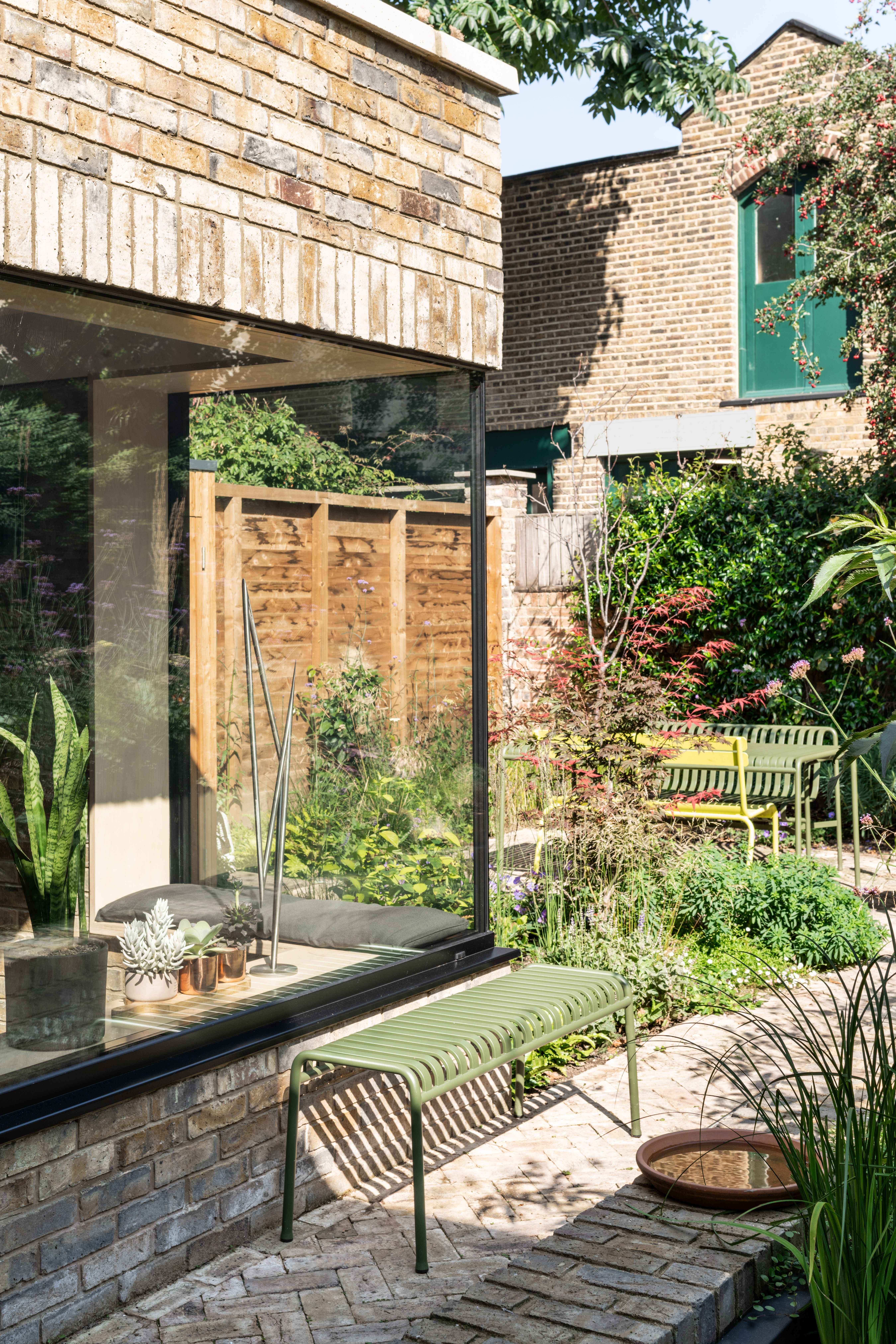 Green Palissade dining furniture by HAY in a small urban garden