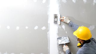 Person plastering joints on plasterboard