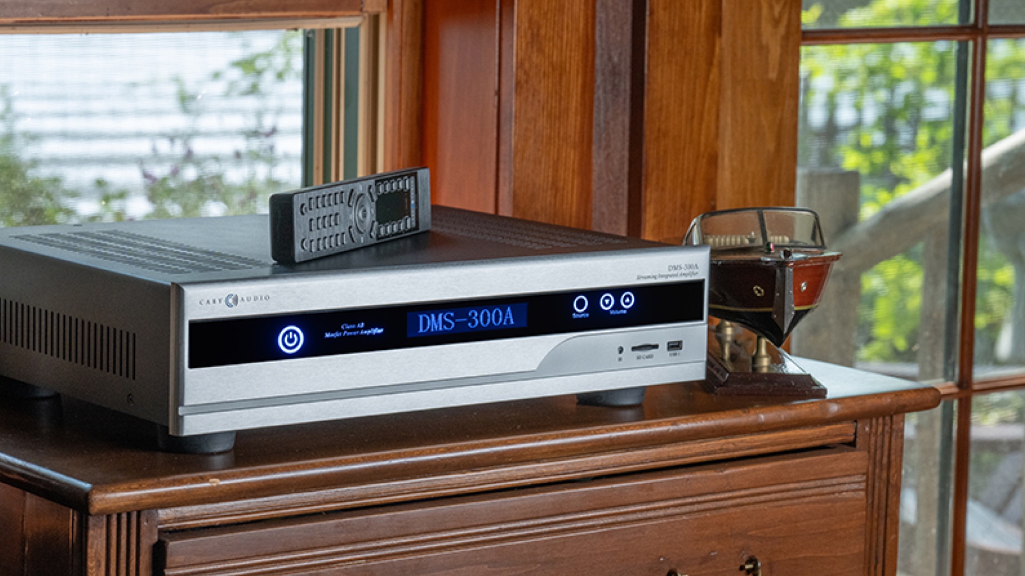 A lifestyle photo of the Cary DMS-300A atop a brown chest of drawers with a model boat next to it
