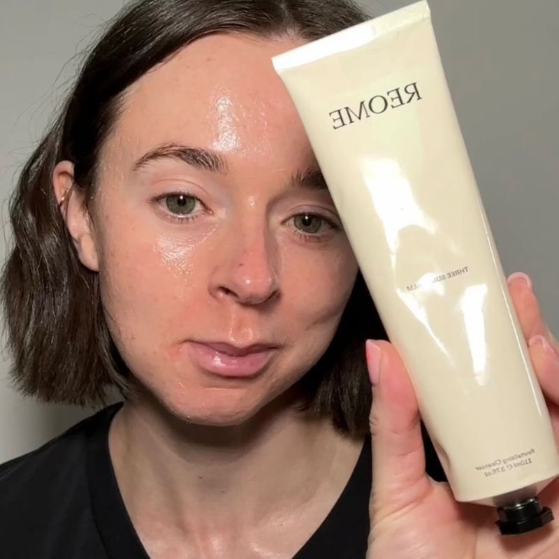 Grace Day with glowy skin holding the Reome cream cleanser