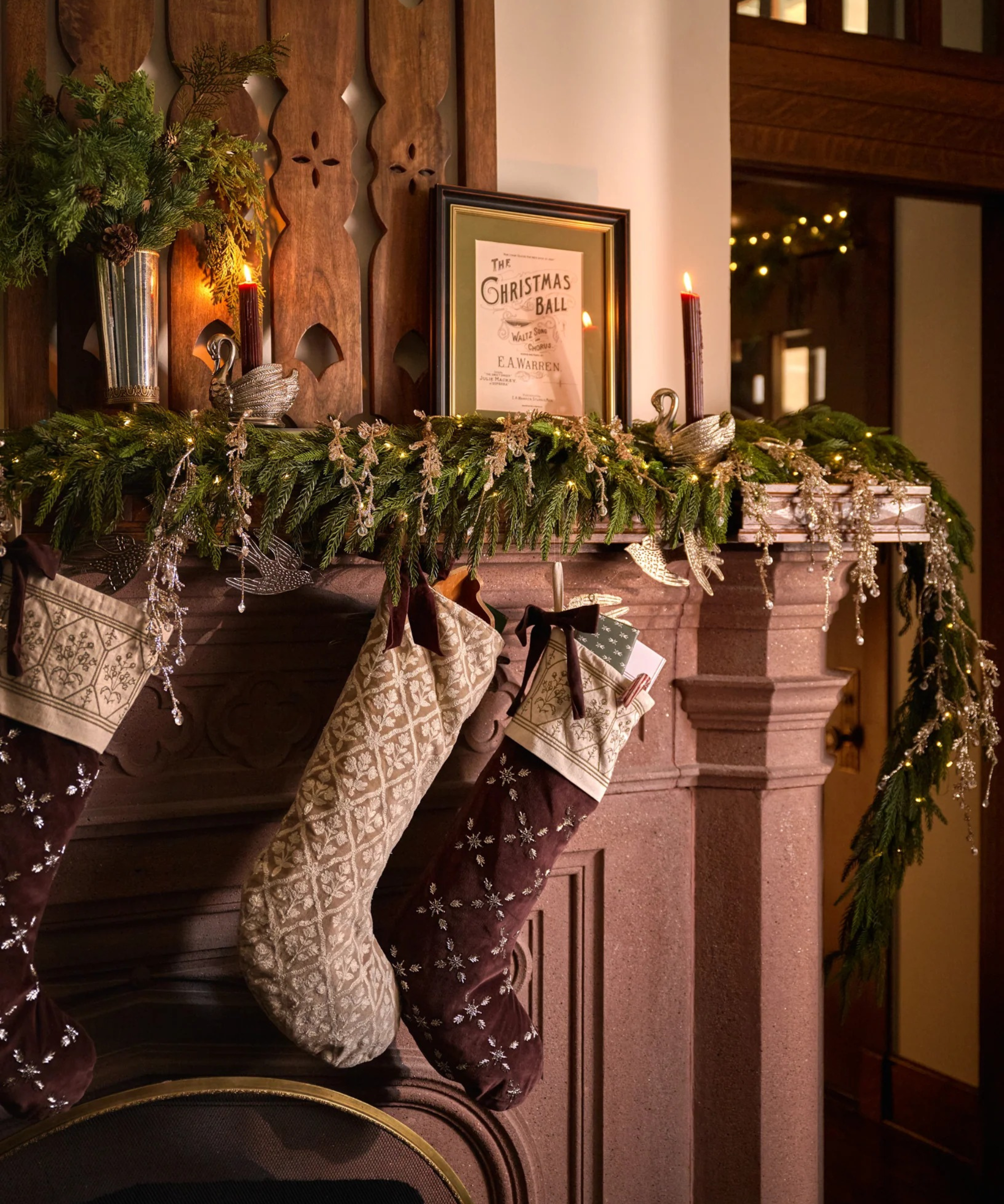 stockings hung from a fireplace mantel with garland and decor for Christmas