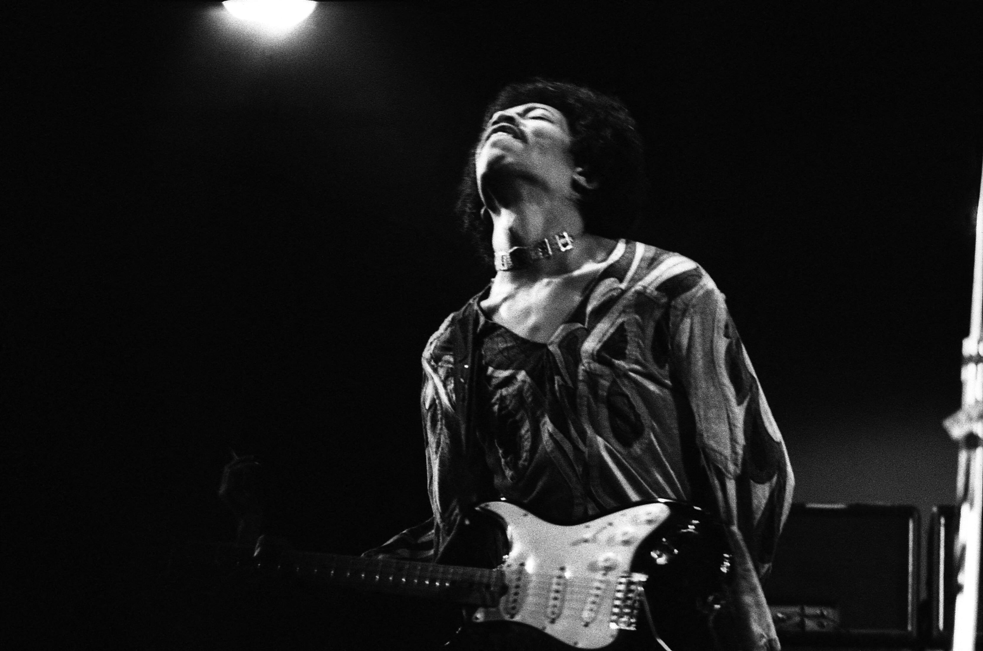 Black and white image of Jimi Hendrix performing on stage