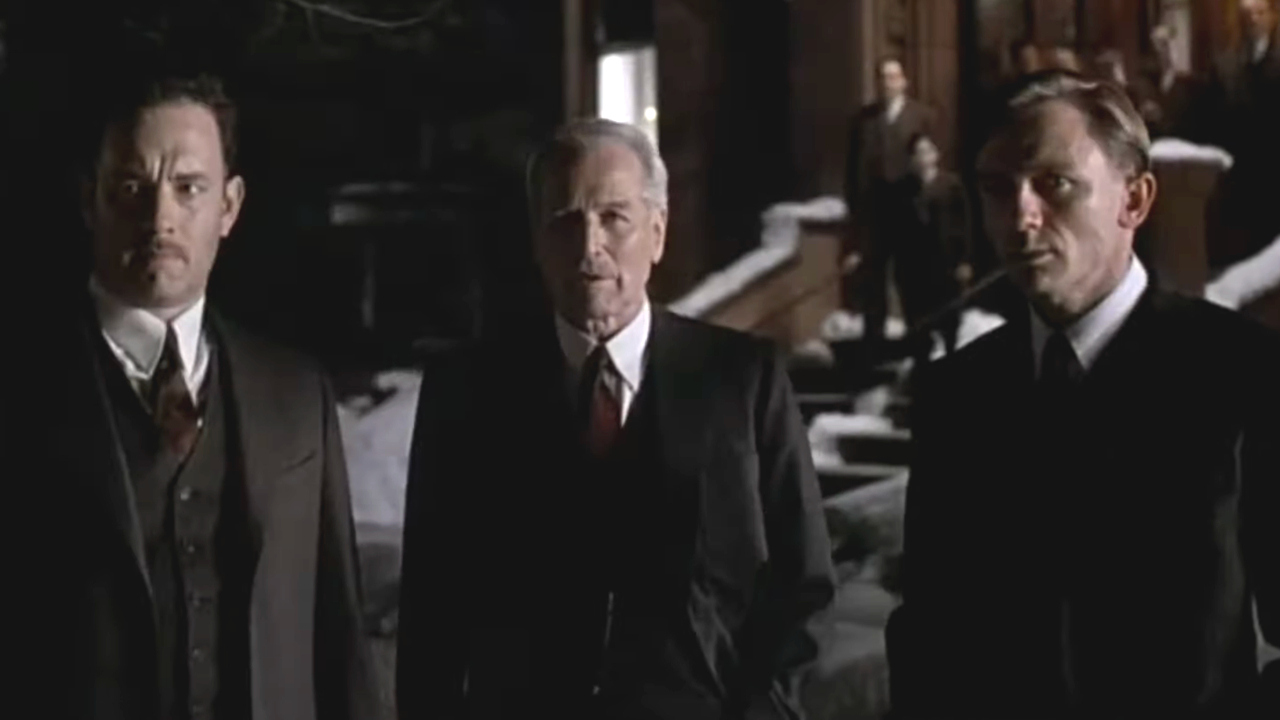 Tom Hanks, Paul Newman, and Daniel Craig standing around together at night in Road to Perdition.