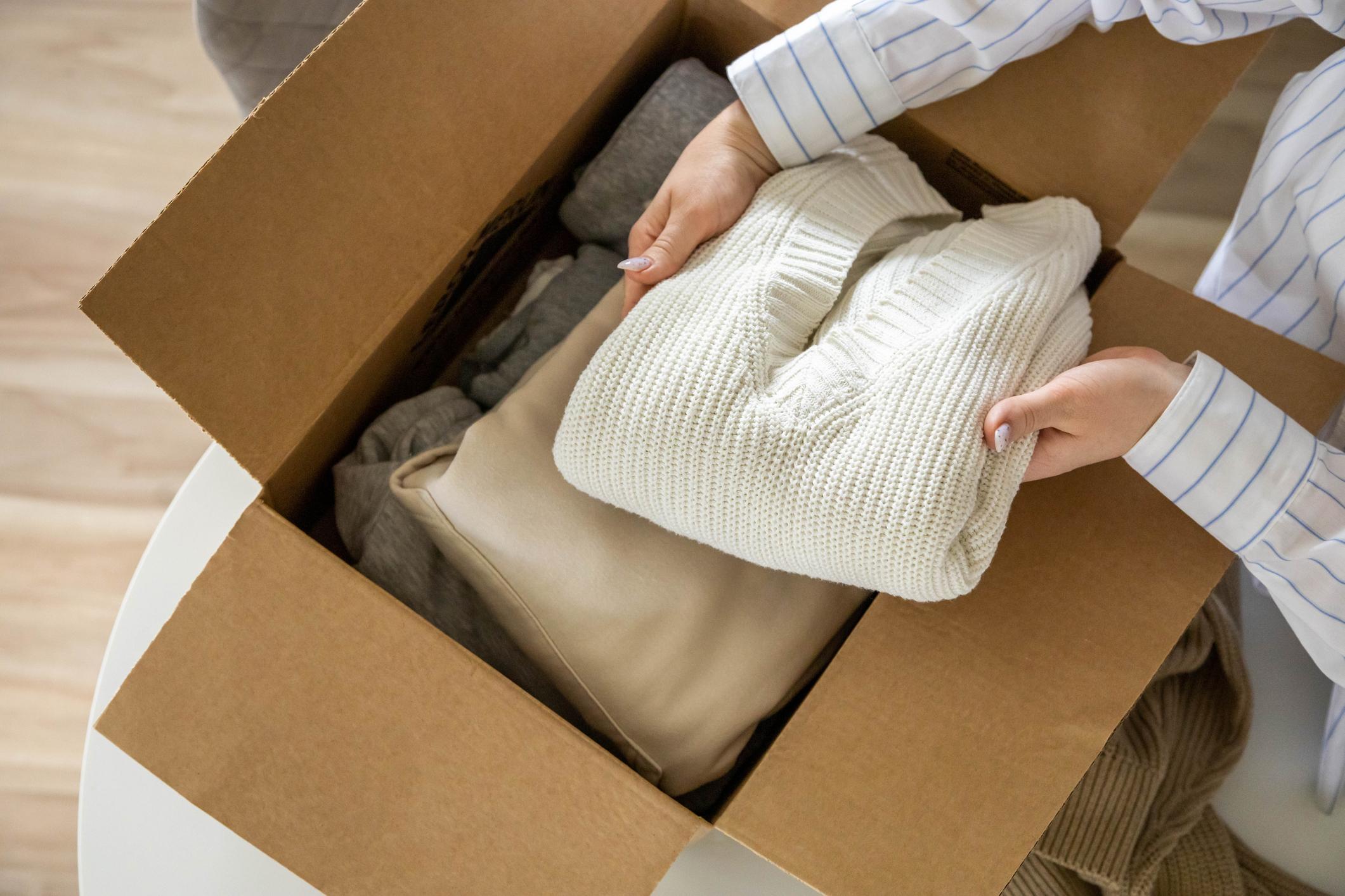  A woman putting folded clothes into a box to sell second-hand. 