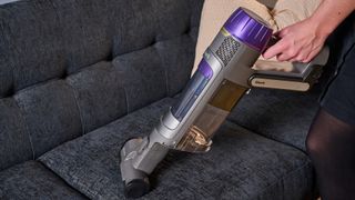 Shark PowerDetect cordless vacuum in handheld mode, being used to clean a sofa