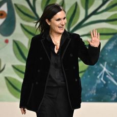 Maria Grazia Chiuri waves to the audience after she steps down from Dior