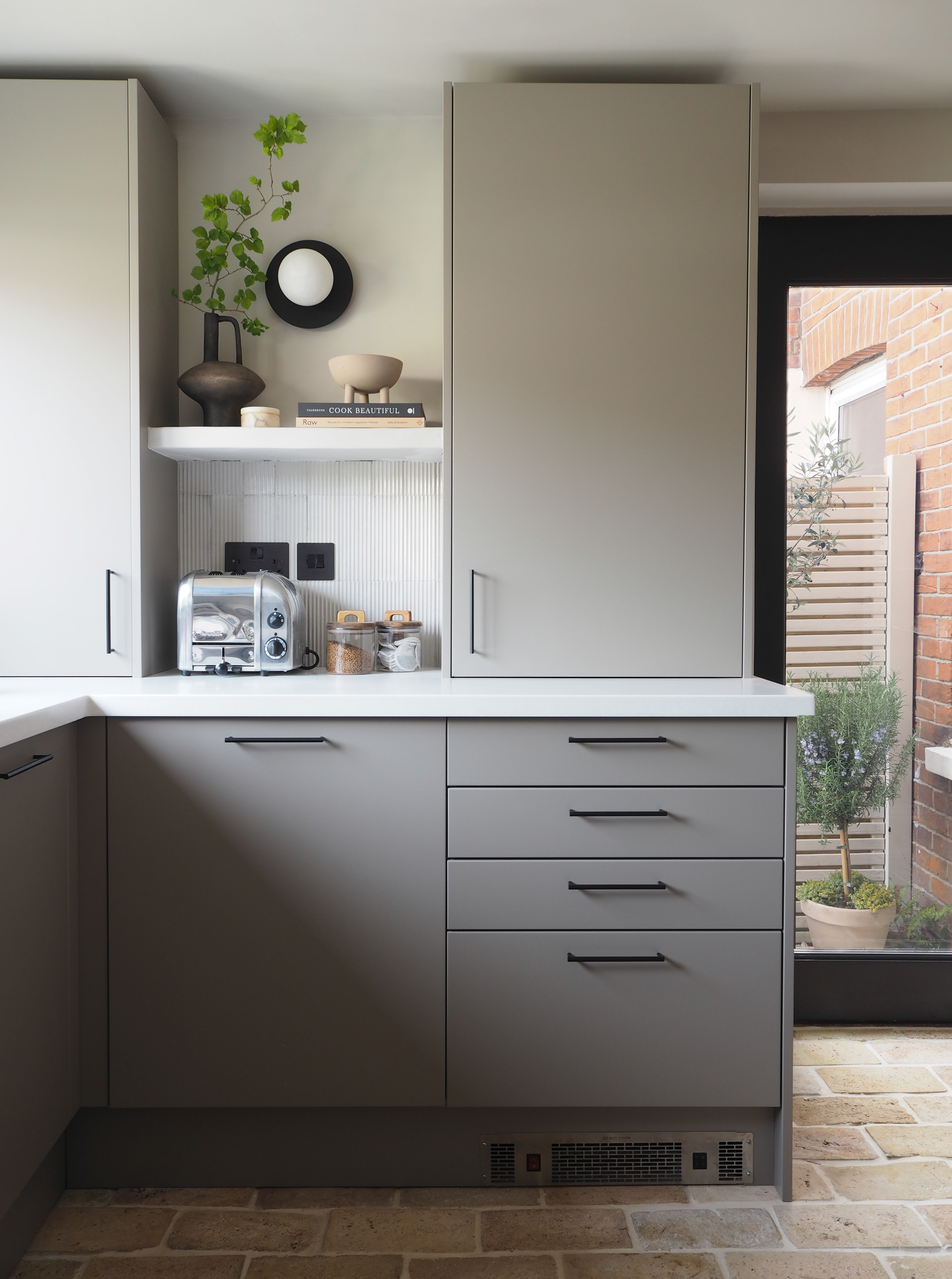 a neutral kitchen with brown kitchen cabinets and a brick floor
