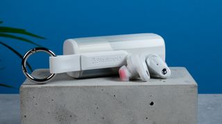 the skullcandy x bose method 360 anc earbuds in white, with a long charging case, a carabiner clip, and various silicone tip sizes