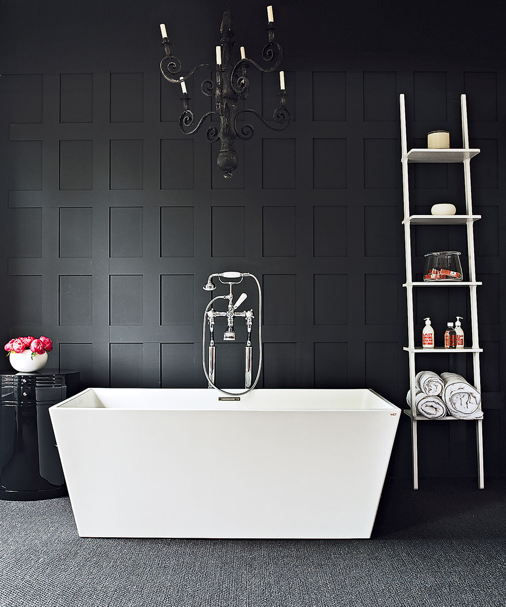 An example of bathroom lighting ideas in a black bathroom with a chandelier over a freestanding contemporary bath