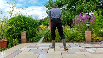 person cleaning a patio with a pressure washer