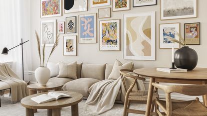 A neutral living room with beige sofa, throw, round dining table and assortment of framed wall art gallery