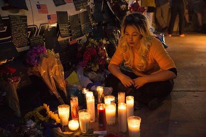 A woman sits by a memorial for slain Dallas police officers