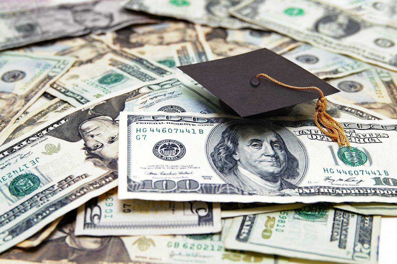 A graduation cap on top of U.S. dollars.