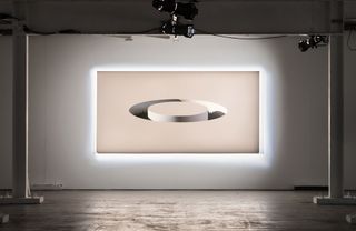 An art installation on canvas. Beige background with a circle in the middle. Reflectors shine on the art piece.