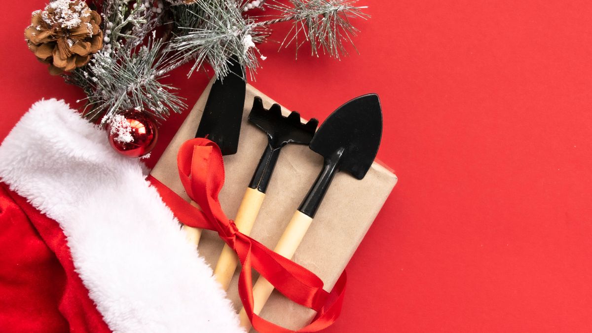 Gardening tools wrapped up as a gift next to a Santa hat 