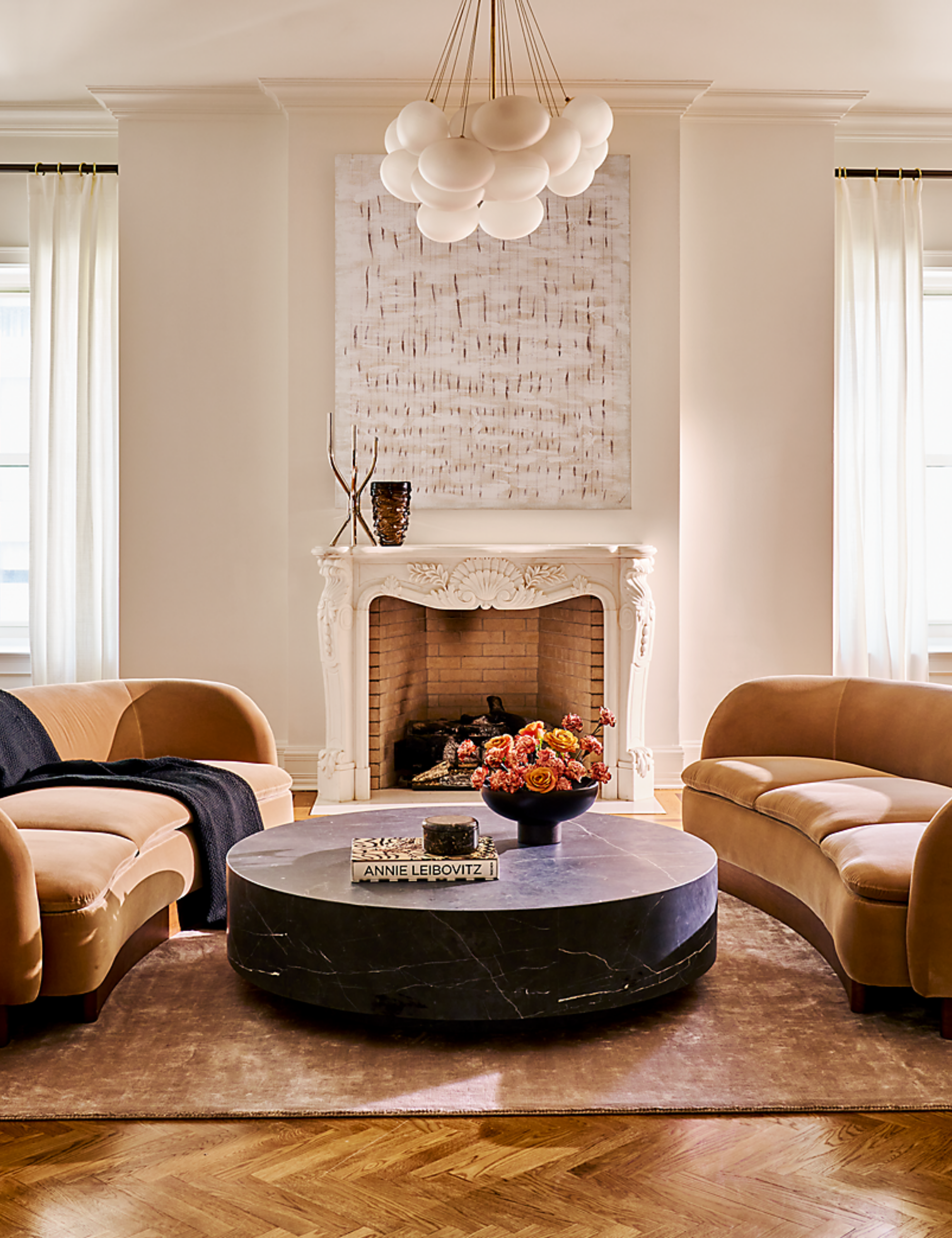 Neutral traditional living room with antique molding, herringbone wood floors, and two contemporary camel velvet curved couches