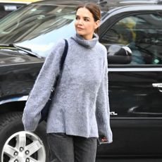 Katie Holmes wears woven ballet flats with a grey jumper and black jeans.