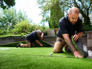 Artificial lawn being laid by two men