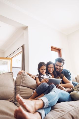 A family huddle together to view a tablet computer screen