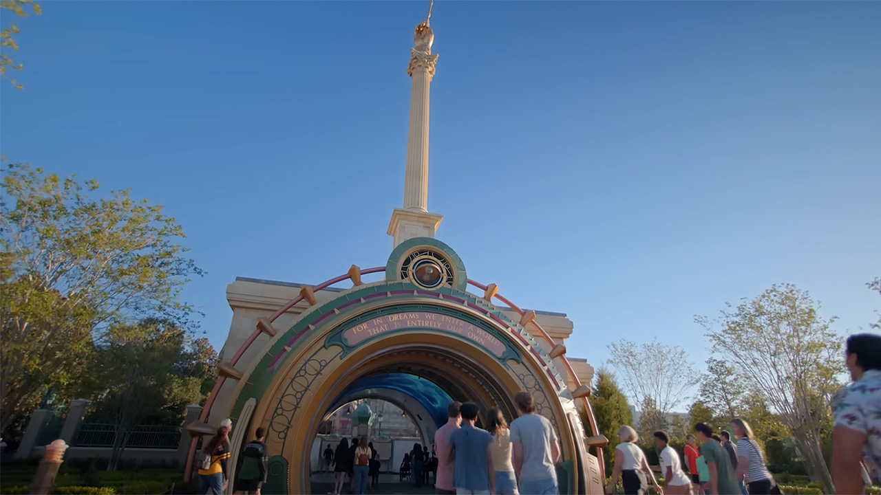 The outside of the Harry Potter portal entrance as people are walking in at Epic Universe with wands.