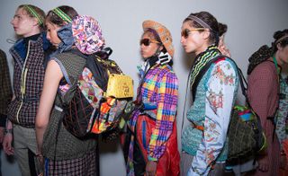 Group of models in colourful clothing & accessories line up for runway