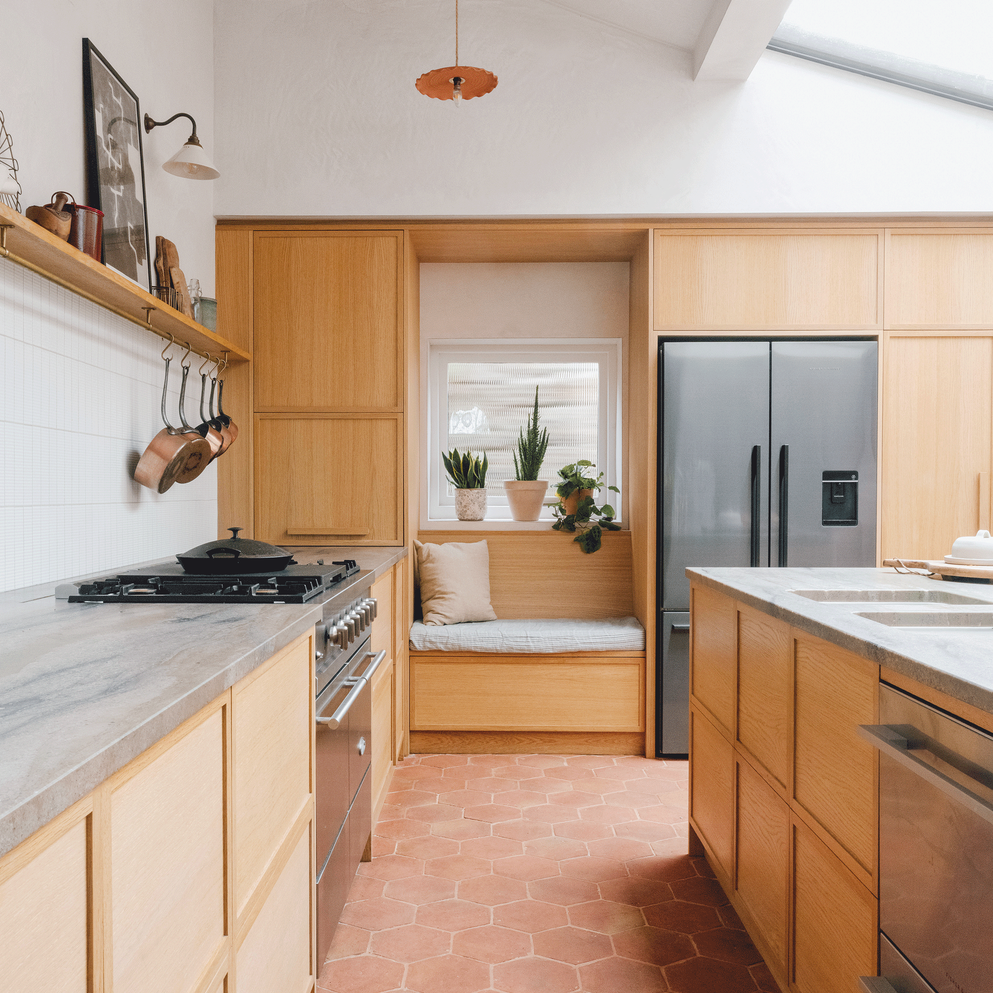 a wooden kitchen with tiled floor with a window seat and a large fridge freezer